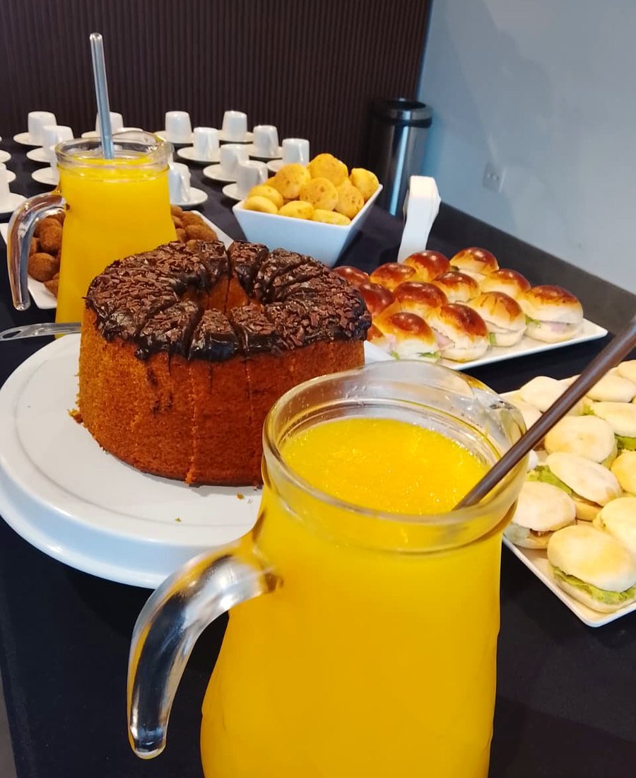 Mesa servida com bolo, suco de laranja e xícaras prontas